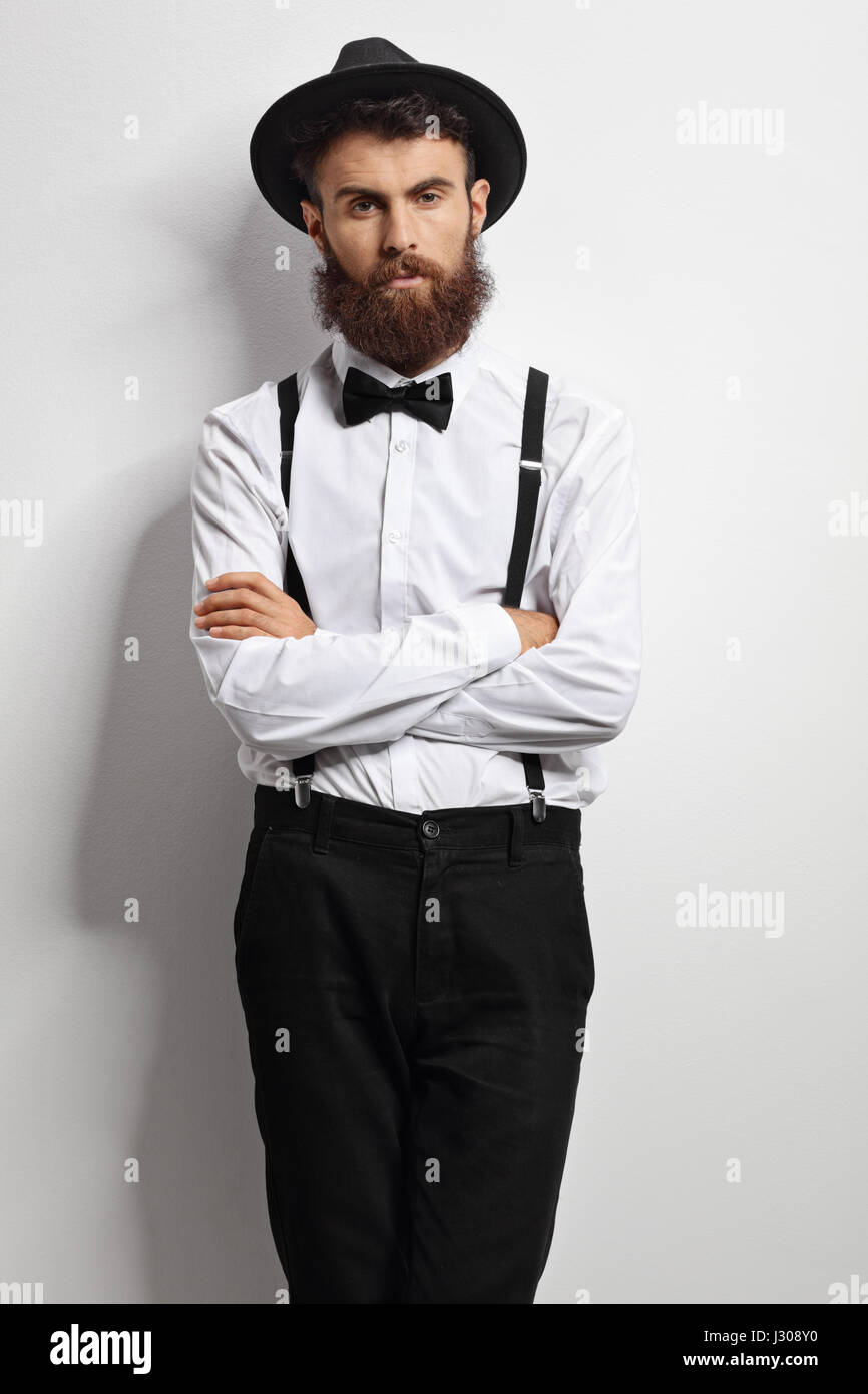 Hombre Barbado con una pajarita y tirantes apoyado una pared blanca Fotografía stock - Alamy