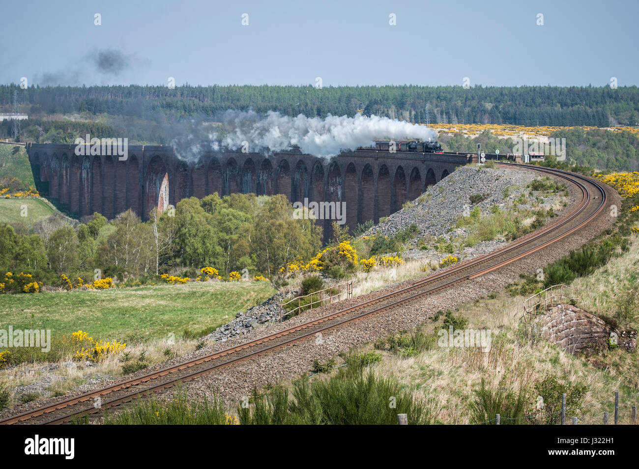 La Gran Bretaña Tour de vapor x goza de cielos azules y despejados mientras cruza viaducto Culloden en la línea principal de la montaña al sur de Inverness. El tren es acarreada por motor y asistida por 62005 45212, trepará Slochd Cumbre (1,315m) en los Cairngorms, la más agotadora subida a toda la red ferroviaria antes de descender a través de Aviemore y continuando al sur de Glasgow. Foto de stock