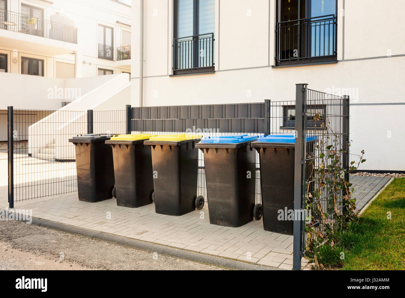 Reciclar los residuos y cubos de basura cerca del nuevo edificio de apartamentos residenciales, la protección del medio ambiente Foto de stock