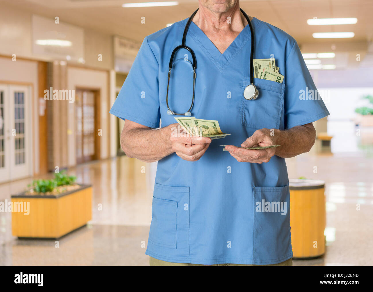 Doctor en scrubs en el hospital contando dinero, salud, seguro de salud, facturas médicas concepto Foto de stock