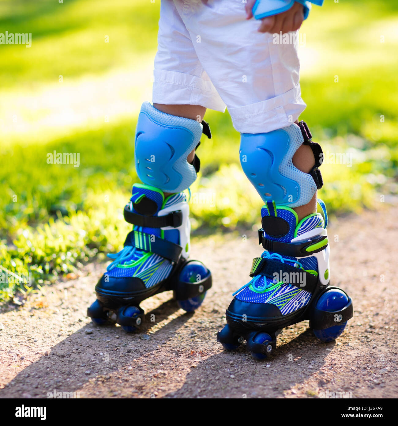 Little Boy aprendiendo a rodillo en verano skate park. Niños vestidos almohadillas de protección segura para patinar paseo. Activa el deporte al aire libre para niños. Clos Foto de stock