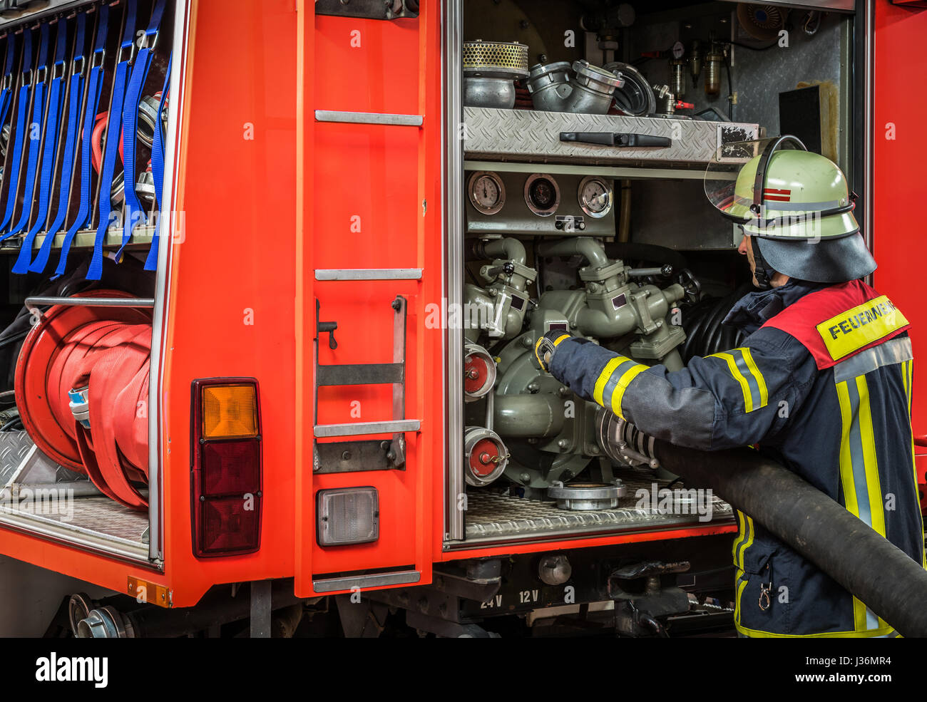 Bombero en acción con una manguera de incendios en el camión de bomberos -  HDR Fotografía de stock - Alamy