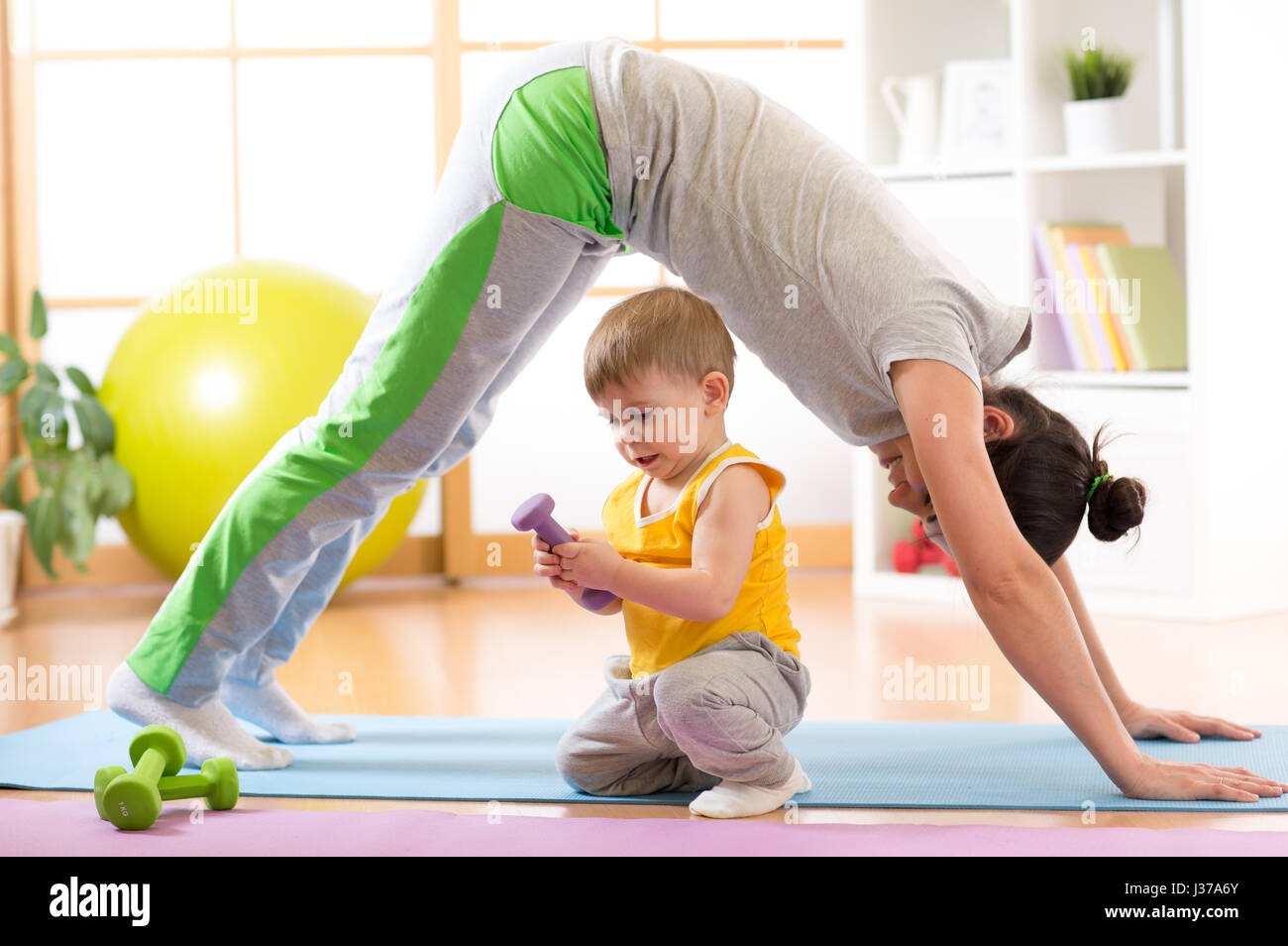 Madre haciendo yoga o ejercicios físicos con el bebé Foto de stock