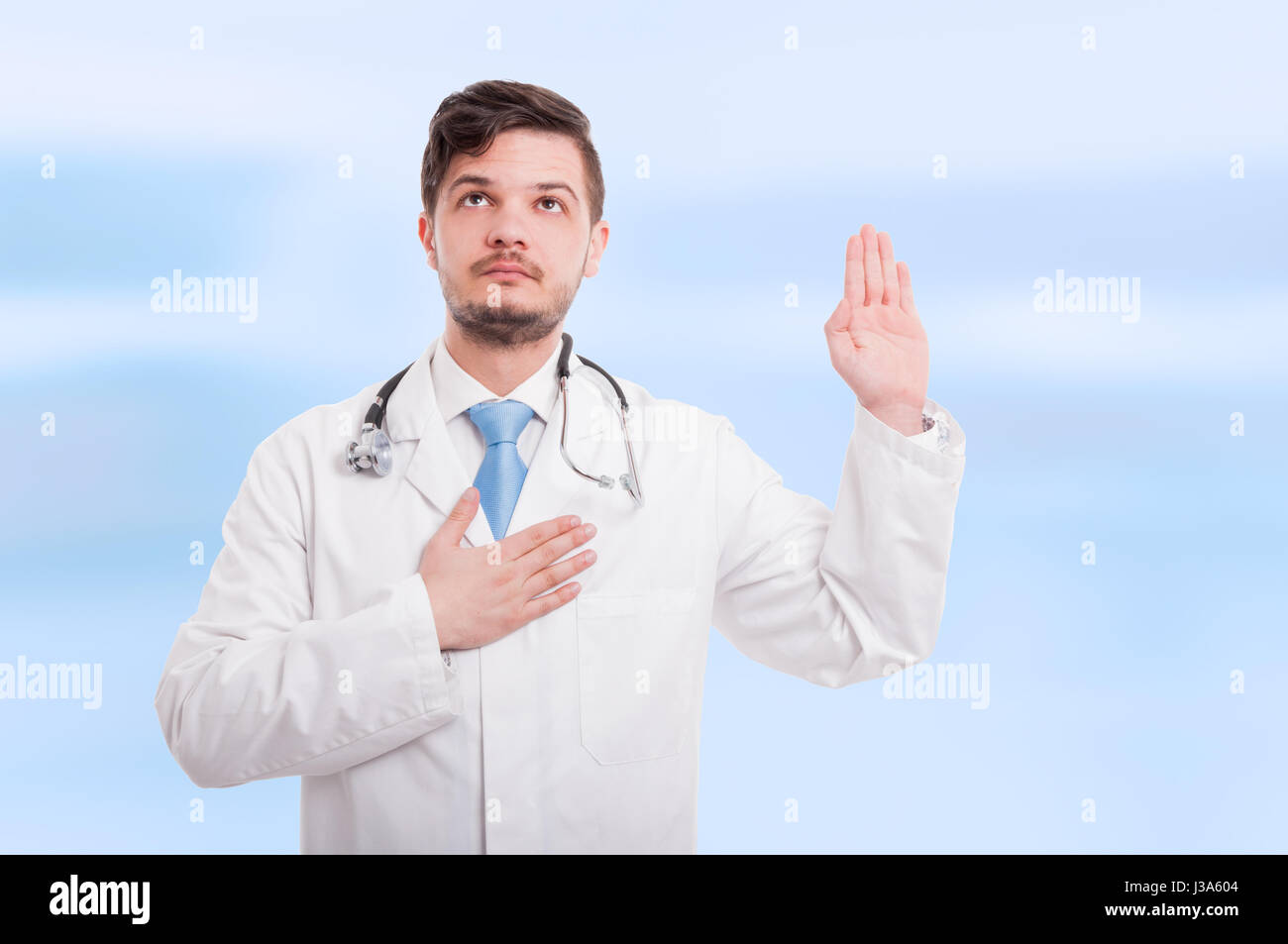Seguro médico aumenta la mano haciendo gestos de lealtad o hacer un juramento sobre fondo azul. Foto de stock