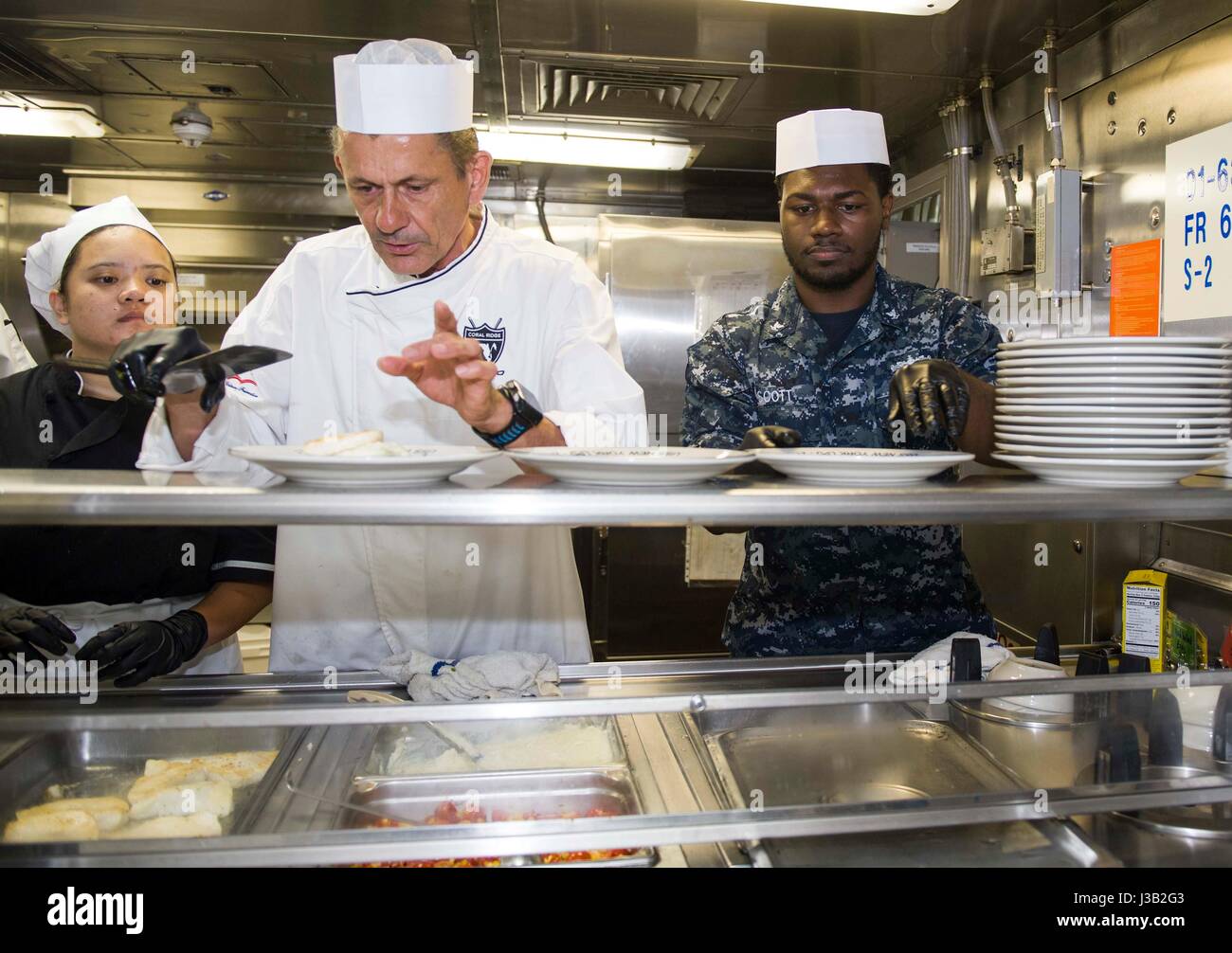 Celebrity Chef Udo Mueller, centro, junto a los marineros de la Marina de EE.UU. preparar el almuerzo a bordo del buque dique anfibio USS New York durante la 27ª Semana de la flota anual el 3 de mayo de 2017 en Port Everglades, Florida. Foto de stock