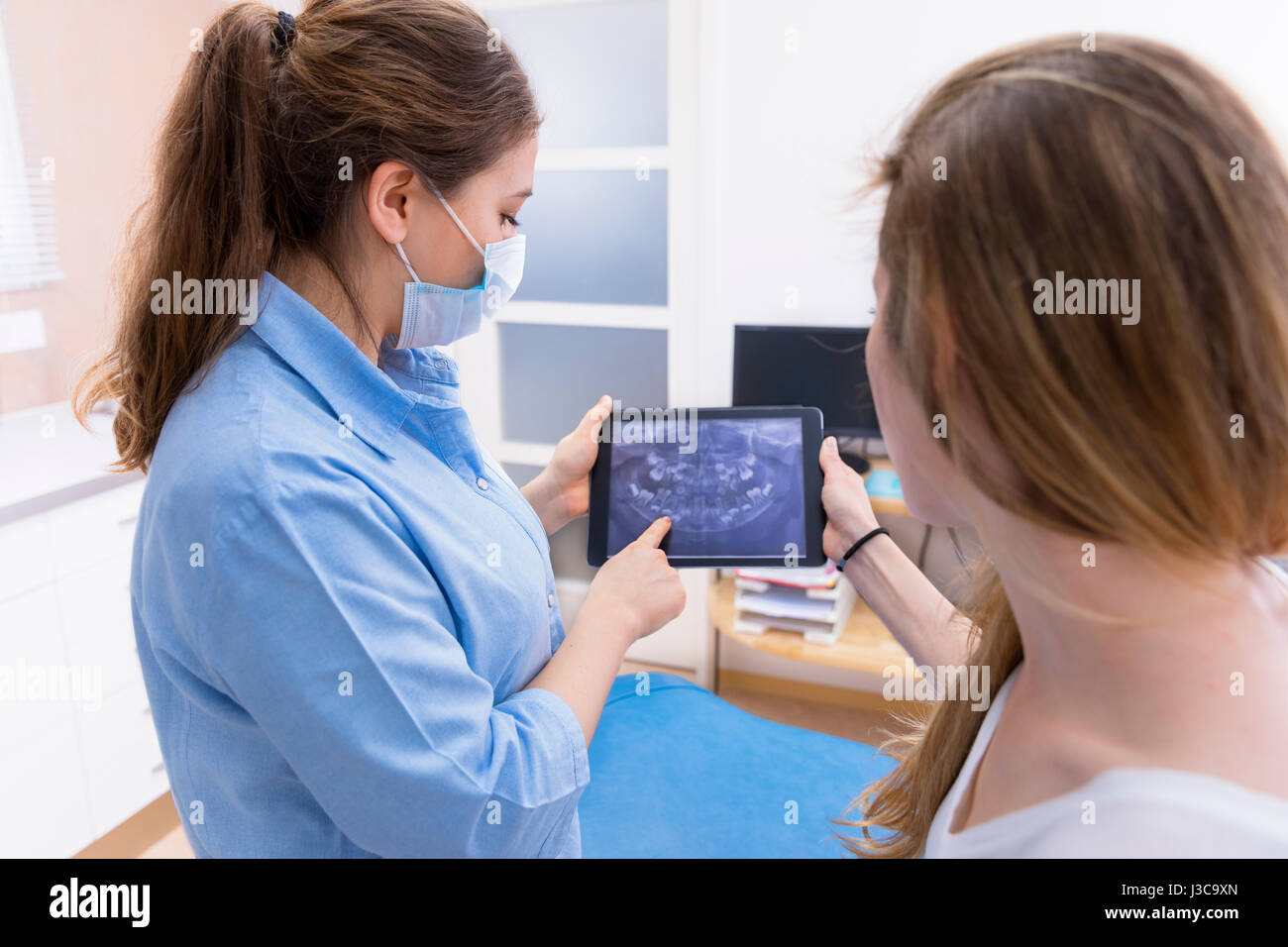 Dentista mostrando teeht Xray el equipo tablet pc al paciente en la clínica dental office