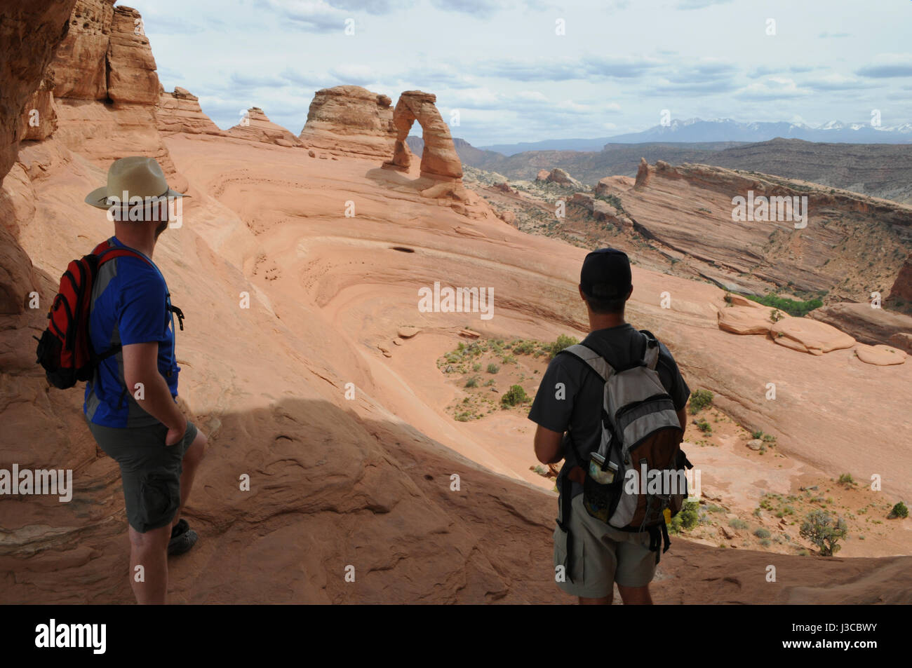 Dos excursionistas mirar hacia el arco delicado en Arches National Park, Moab, Utah. Éstas son las dos únicas personas disfrutando de esta visión expansiva. Foto de stock