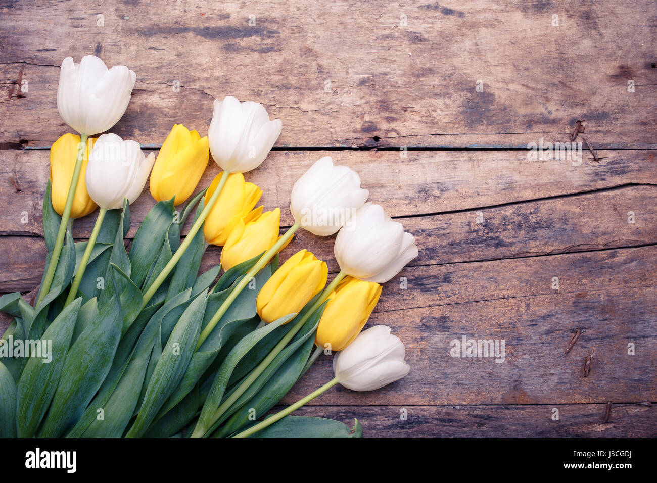 Ramo de tulipanes blancos y amarillos sobre la mesa de madera. Tarjeta de  cumpleaños antecedentes Fotografía de stock - Alamy