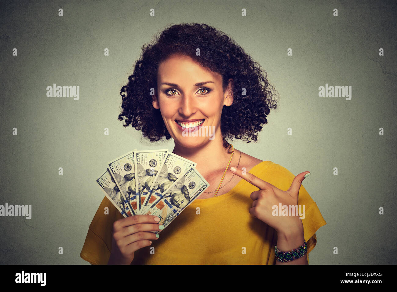 Closeup retrato super feliz emocionado exitosa mujer de negocios jóvenes sosteniendo dinero billetes de dólar en mano aislados de pared gris de fondo. Emotio positivo Foto de stock