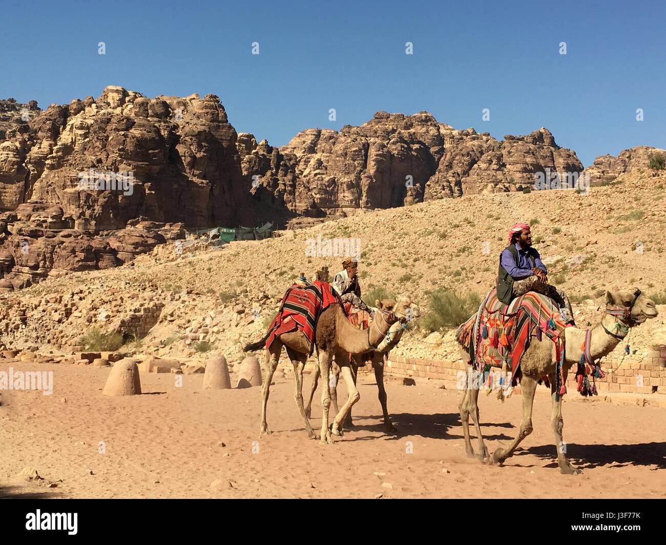 Los jinetes de camellos árabes y beduinas en Petra sitio del Patrimonio Mundial en Jordania, Oriente Medio Foto de stock
