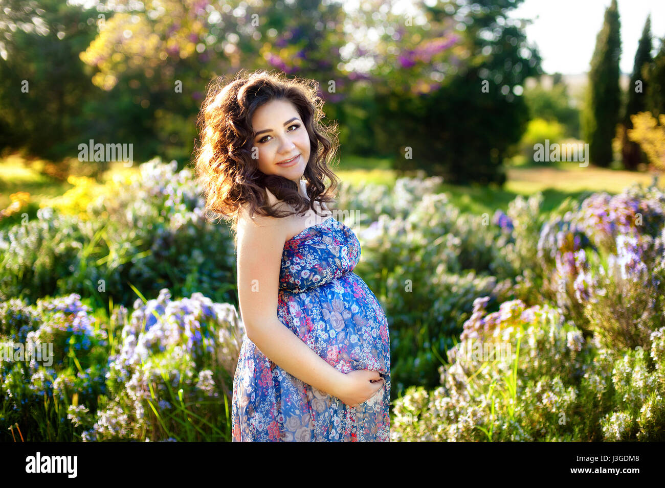 La mujer embarazada en el florido jardín de primavera. Disparar el embarazo y la maternidad de la mujer. Foto de stock