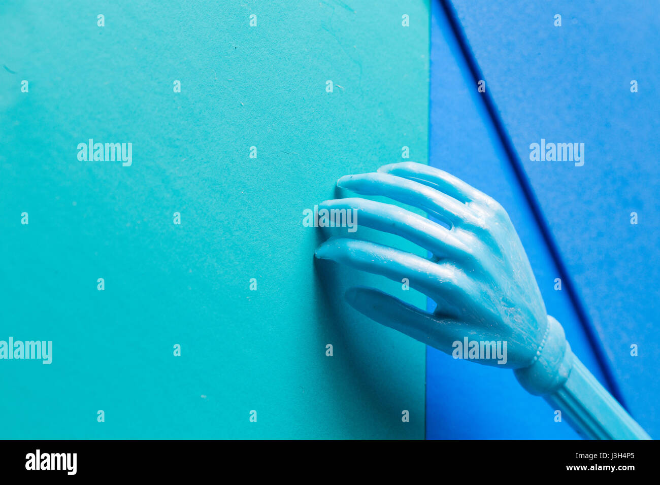 Su vida en tonos de azul: sigue la vida de un plástico mini mano colocado en un tono de múltiples tonalidades de azul. Foto de stock