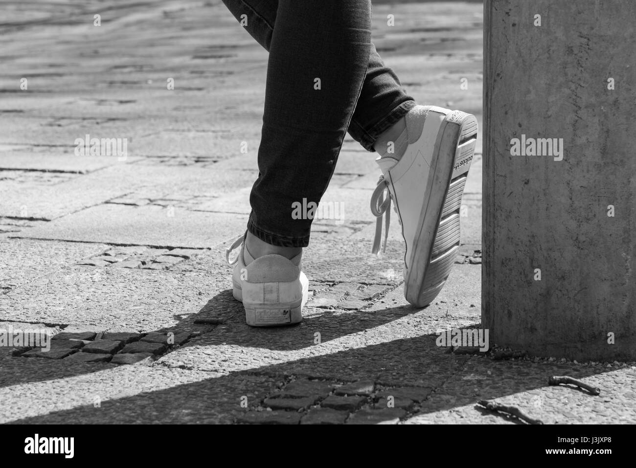 Alemania, Munich, 25 de marzo de 2017, una bella mujer es vestir de blanco  zapatillas de Adidas y se inclina contra una linterna Fotografía de stock -  Alamy