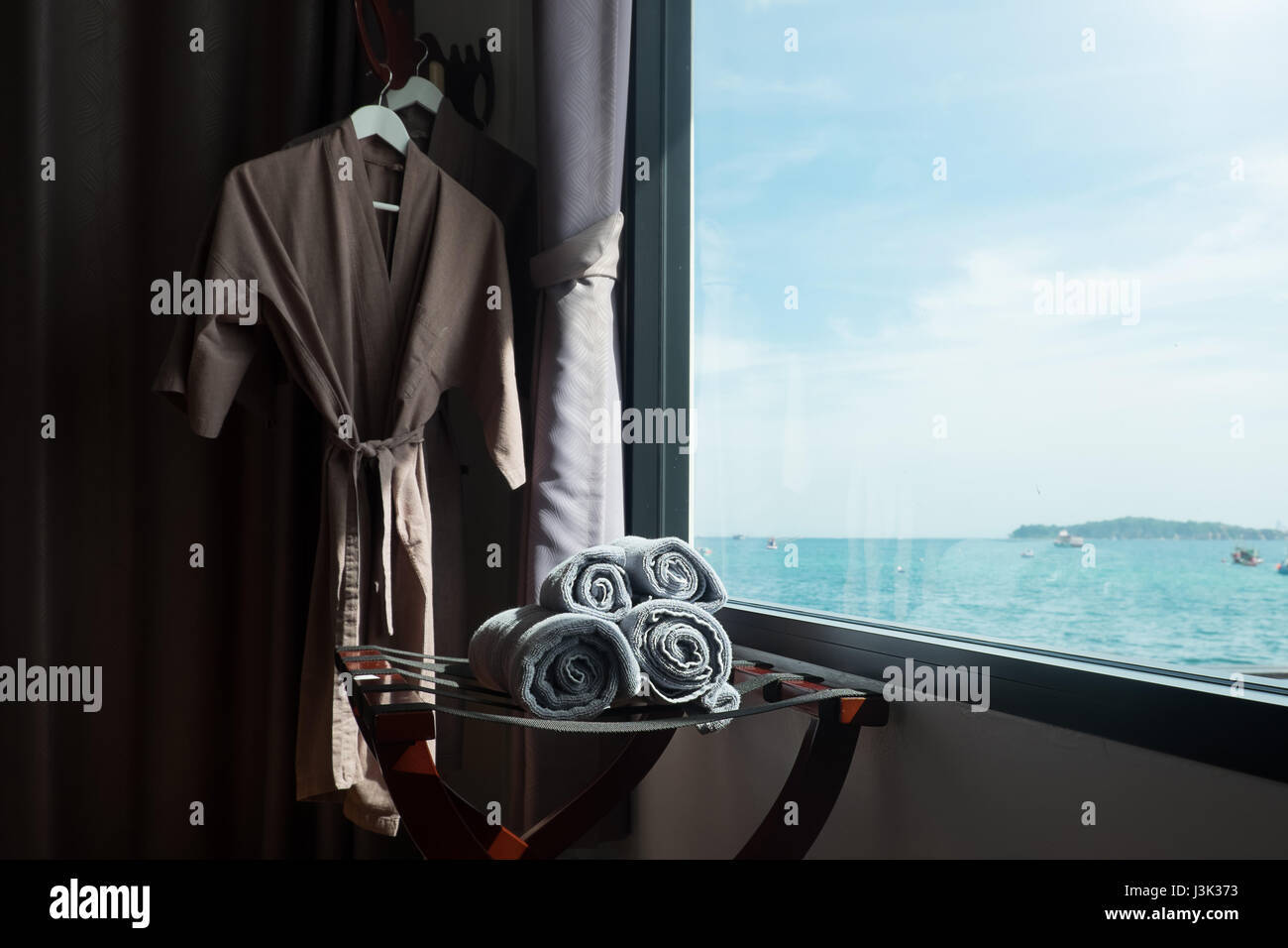 Una toalla enrollada en la habitación con vistas al mar scape en windows tonos oscuros y tonos vintage, concepto de vacaciones. Foto de stock