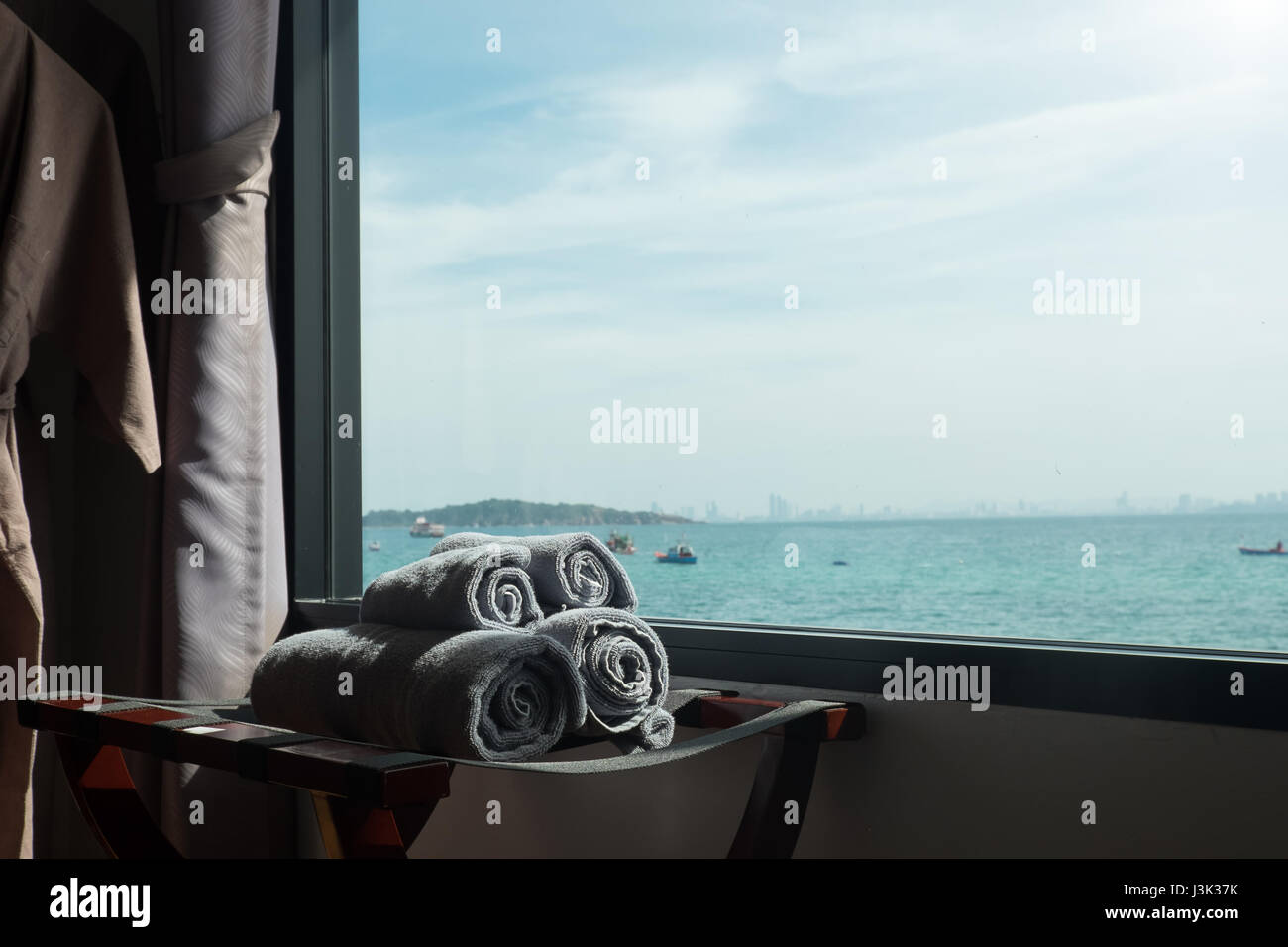 Una toalla enrollada en la habitación con vistas al mar scape en windows tonos oscuros y tonos vintage, concepto de vacaciones. Foto de stock
