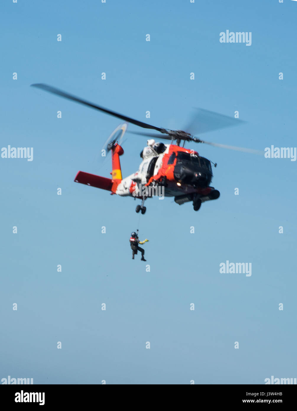 Una tripulación de Air Station San Diego es subirla un miembro hasta un guardacostas Jayhawk MH60 helicóptero de rescate durante el acantilado la formación fuera del acantilado del punto Vicente Faro en Rancho Palos Verdes, California el 26 de abril de 2017. La formación contribuye consistentemente las tripulaciones estancia adepto de situaciones donde tendrán que realizar un acantilado de rescate. (Ee.Uu. Coast Guard foto por Suboficiales DaVonte 3ª clase' ósea) Foto de stock