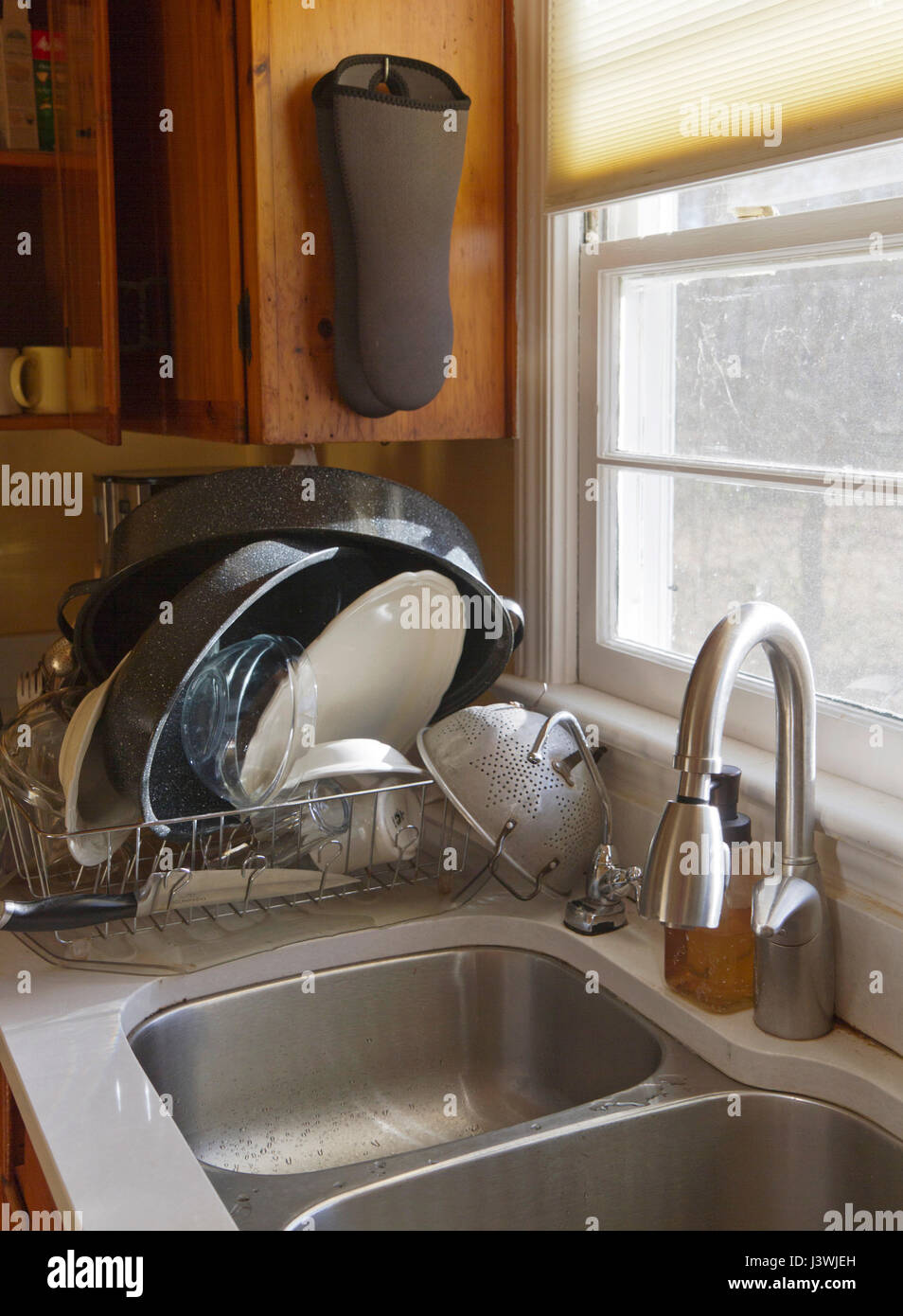 Una pila de lavar platos a mano secado en un plato el drenaje del fregadero  en el sol de la mañana que entra a través de una ventana Fotografía de  stock -