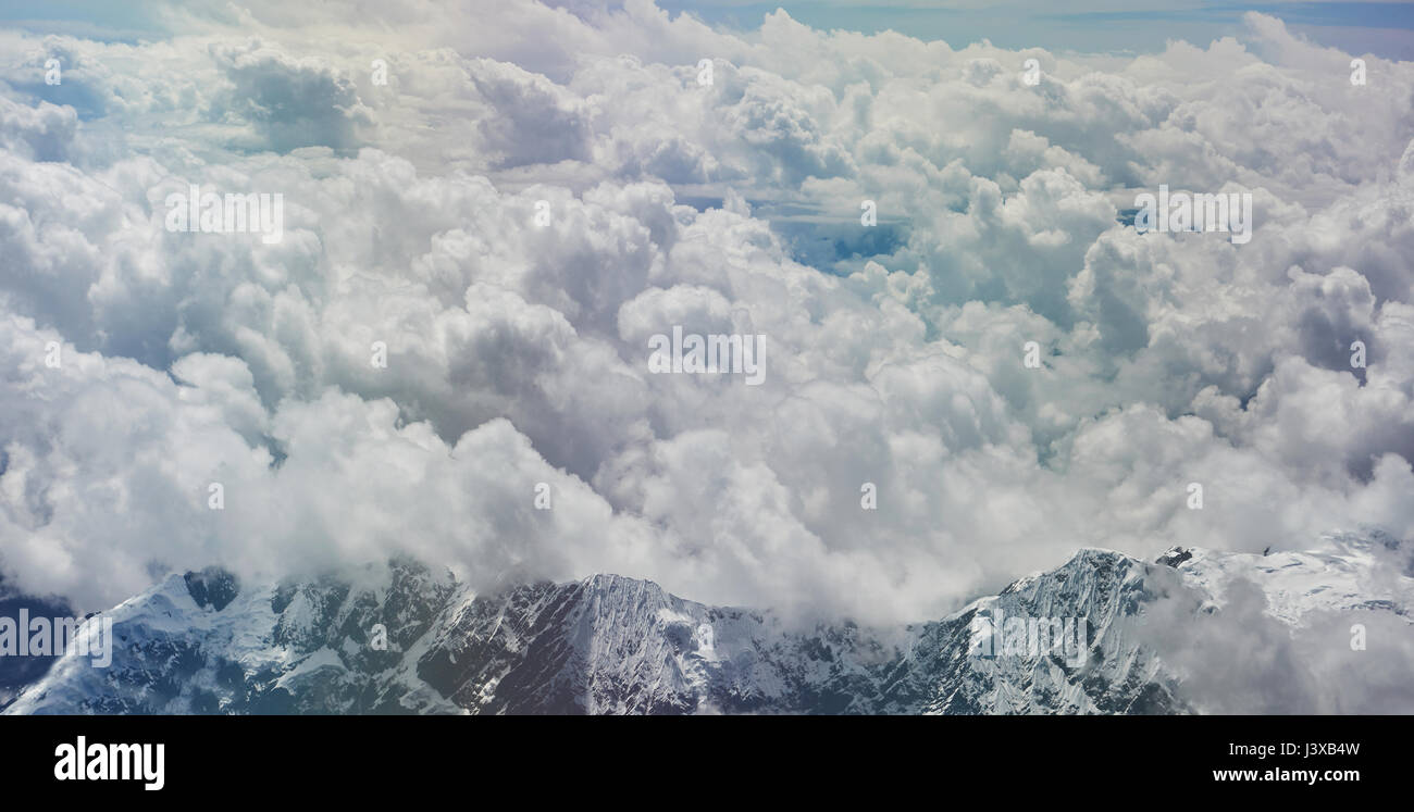 Fila de montaña con nieve en grandes nubes blancas vista aérea Foto de stock