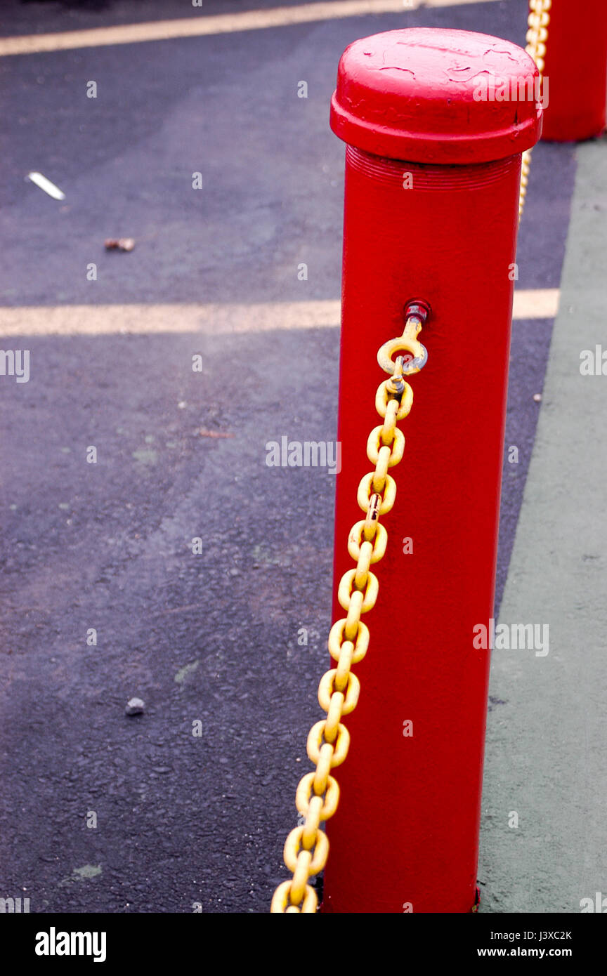 Un paragolpes color rojo brillante amarillo post con la cadena. Barrera de  parking con plazas de aparcamiento detrás de él Fotografía de stock - Alamy