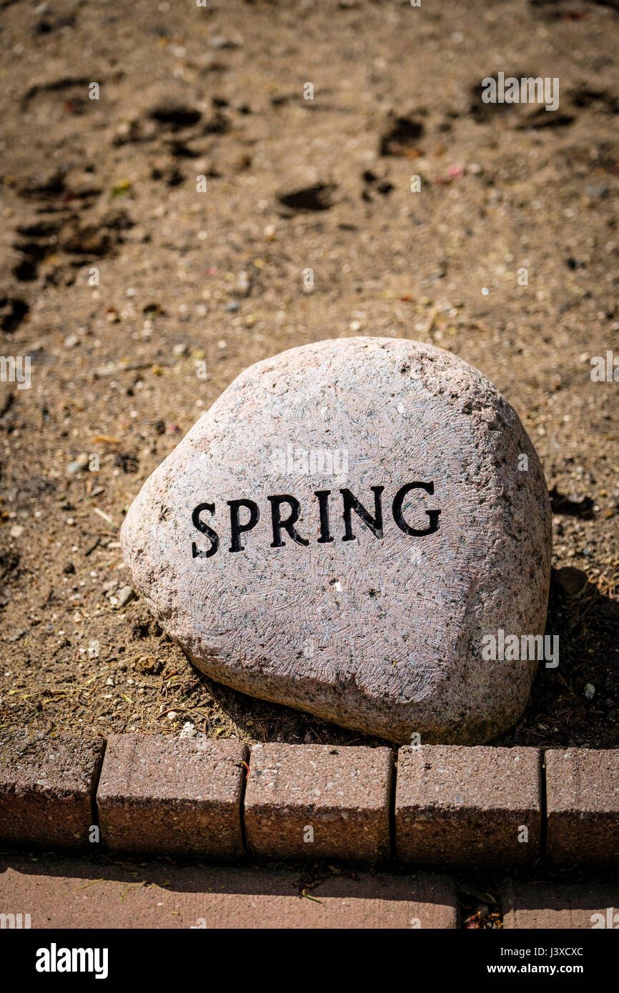 Muelle de la palabra escrita, grabado, repujado, en un jardín decorativo piedra, estaciones del año, decoración, jardín de piedra, piedra ornamental, signo de primavera. Foto de stock