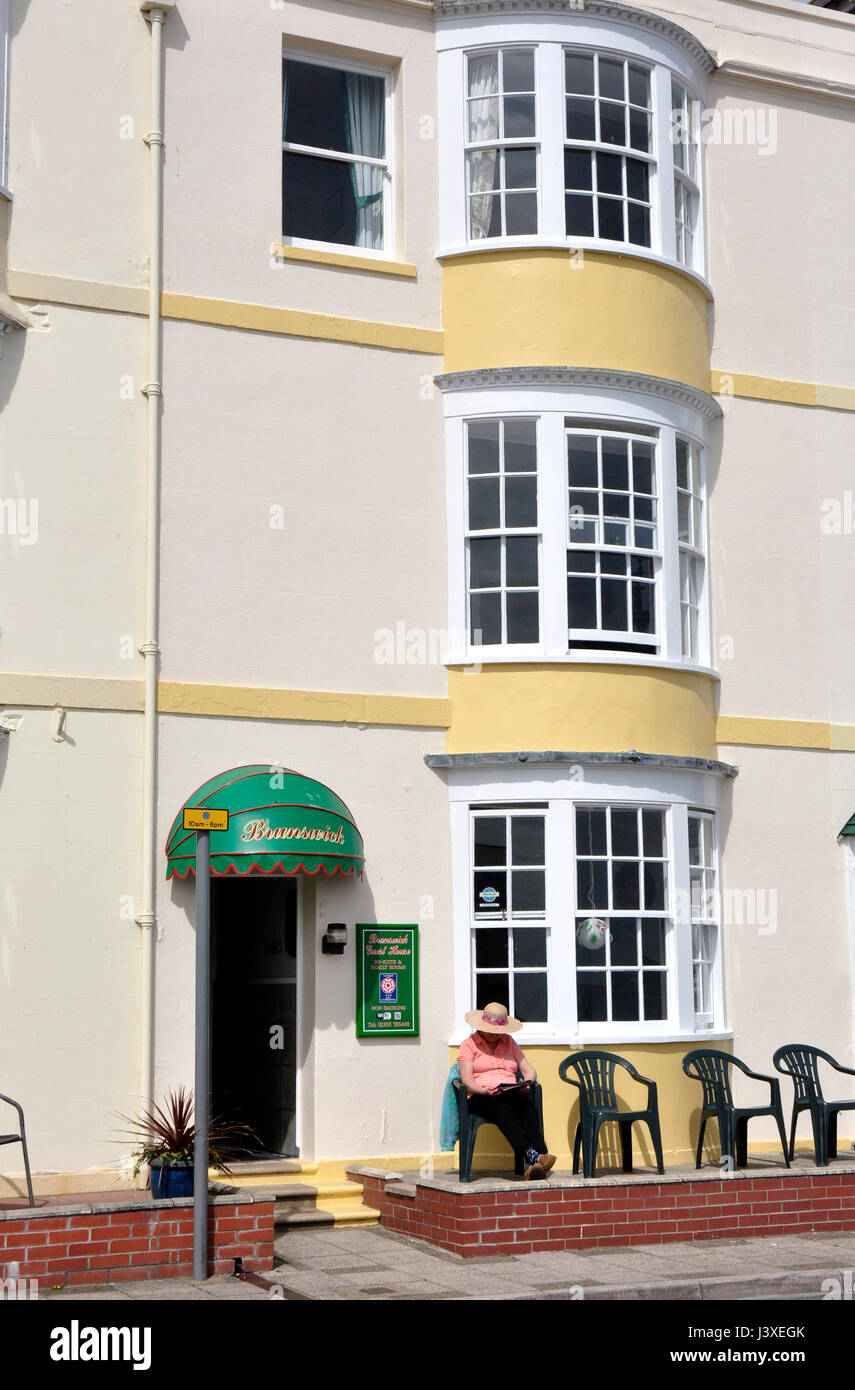 Pequeño hotel de época mar Weymouth Dorset - resident sentado fuera de lectura - disfrutando del sol- bow windows - Puerta abierta - invitar Foto de stock
