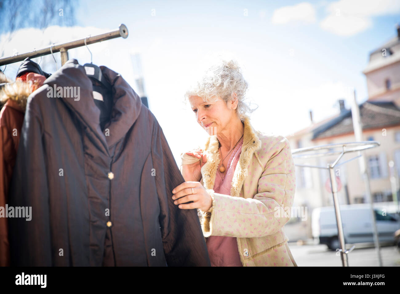 Mujer madura shopper mirando ropa en el mercado local. Foto de stock
