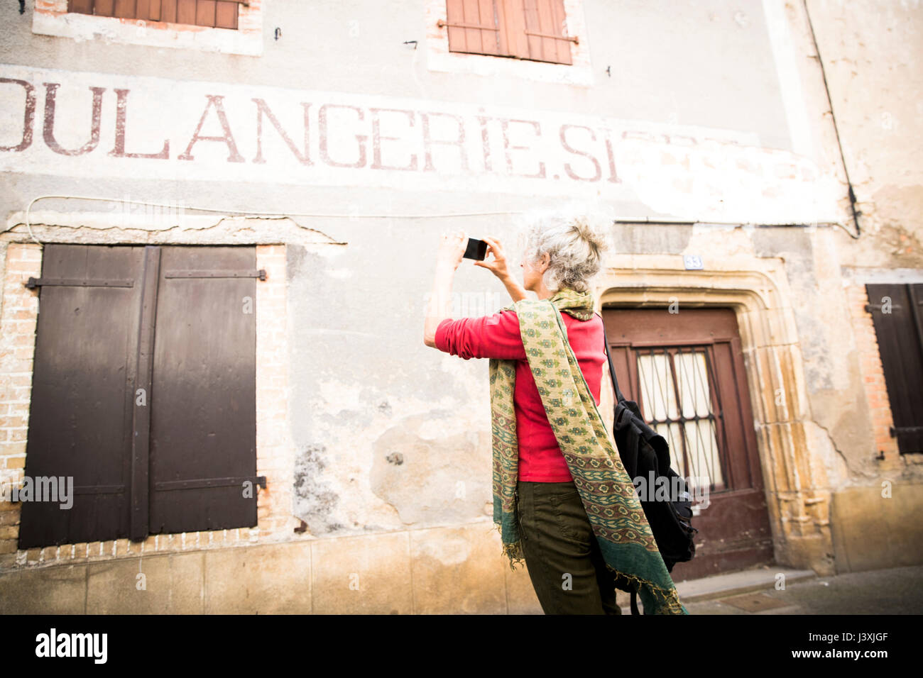 Mujer toma la fotografía de los carteles en la construcción exterior, Bruniquel, Francia Foto de stock