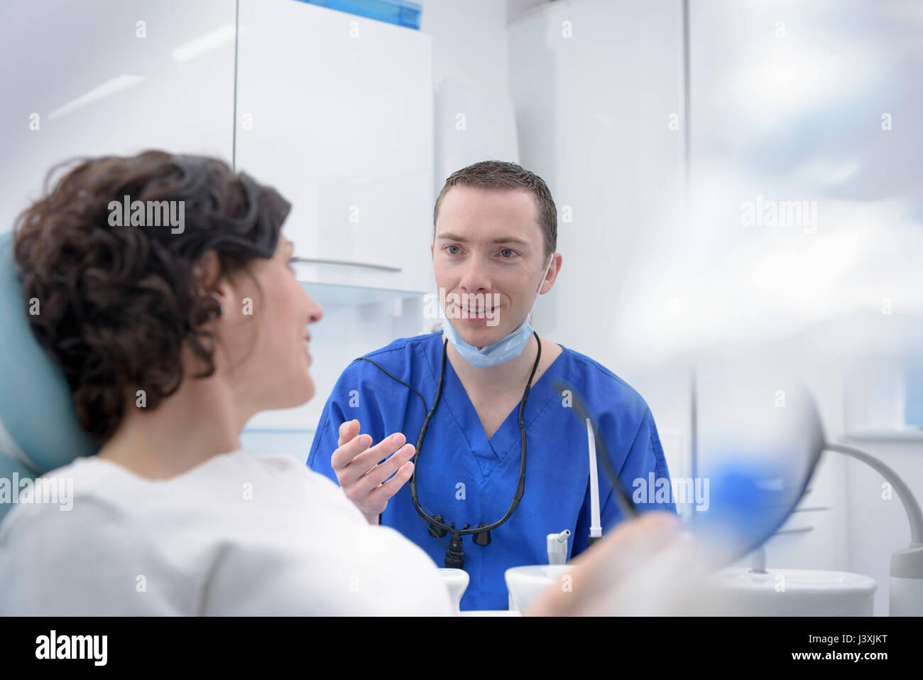 Dentista hablando al paciente en la sala de tratamientos de cirugía dental Foto de stock