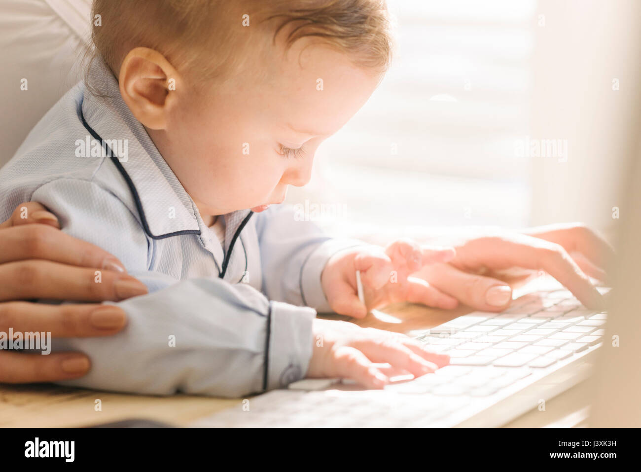 Madre escribiendo con el bebé busca interesados en teclado Foto de stock