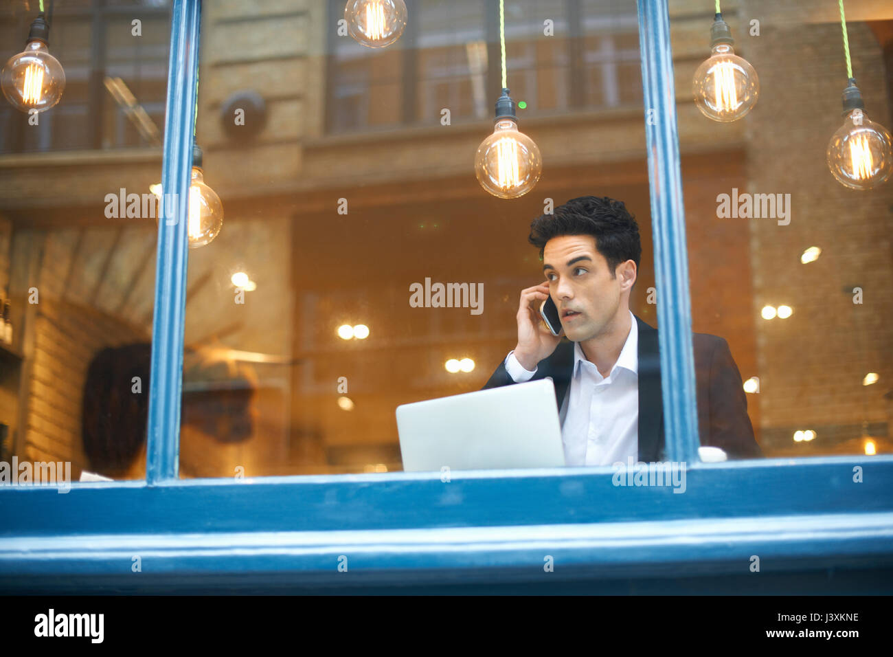 La vista de la ventana del empresario haciendo llamada smartphone en cafe Foto de stock