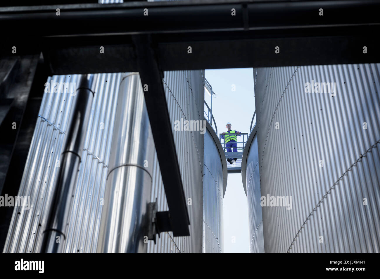 Trabajador en la parte superior de los tanques de almacenamiento de aceite en la fábrica de fusión Foto de stock