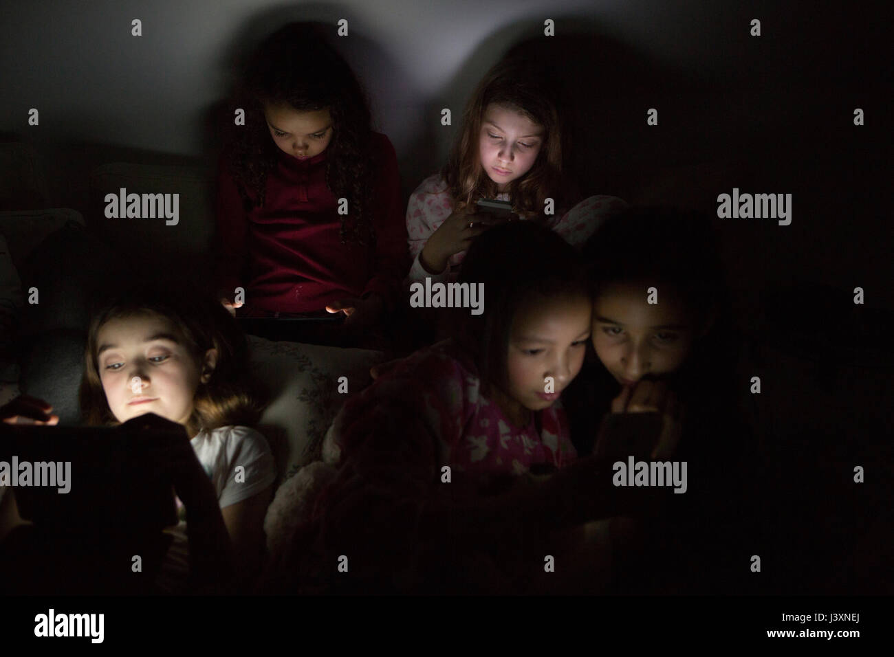Las niñas en oscuridad a Slumber Party iluminada por tableta digital Foto de stock