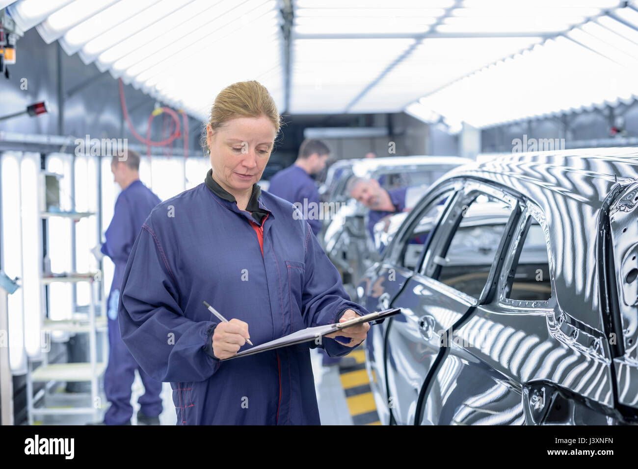 Inspector femenino en el taller de pintura en la fábrica de automóviles Foto de stock