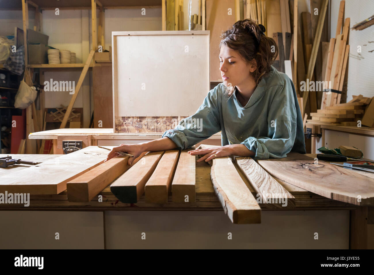 Mujer joven eligiendo la madera de una selección en un taller Foto de stock