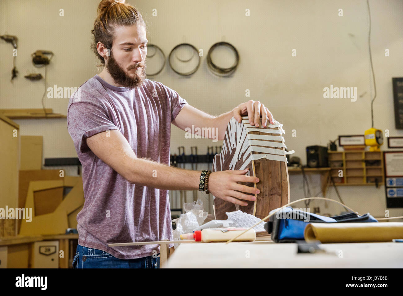 Joven construyendo una guitarra acústica en un taller Foto de stock