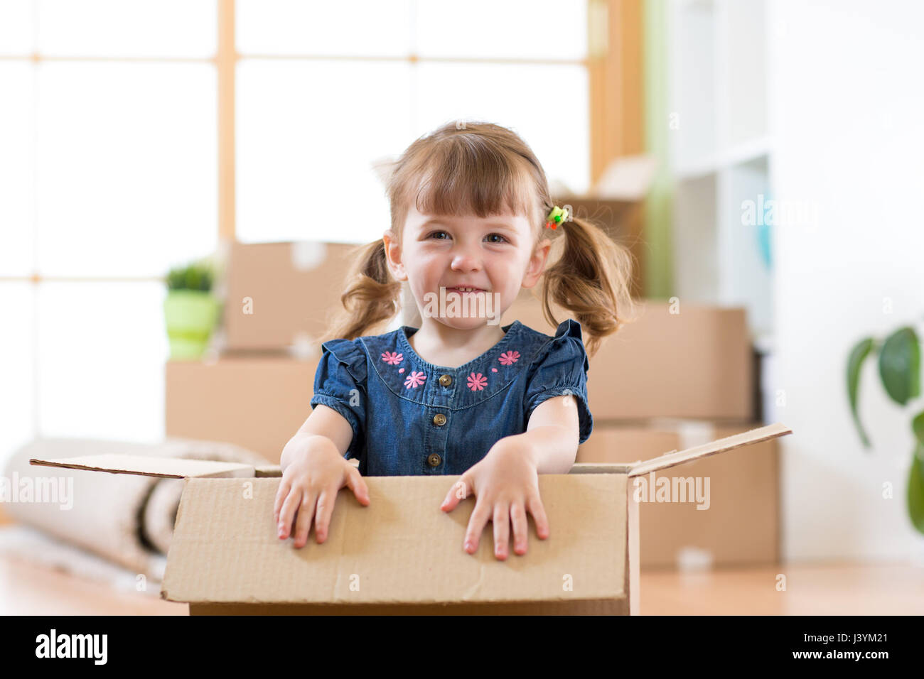 Acaba de mudarse a una nueva casa. Kid se encuentra dentro de la caja. Foto de stock