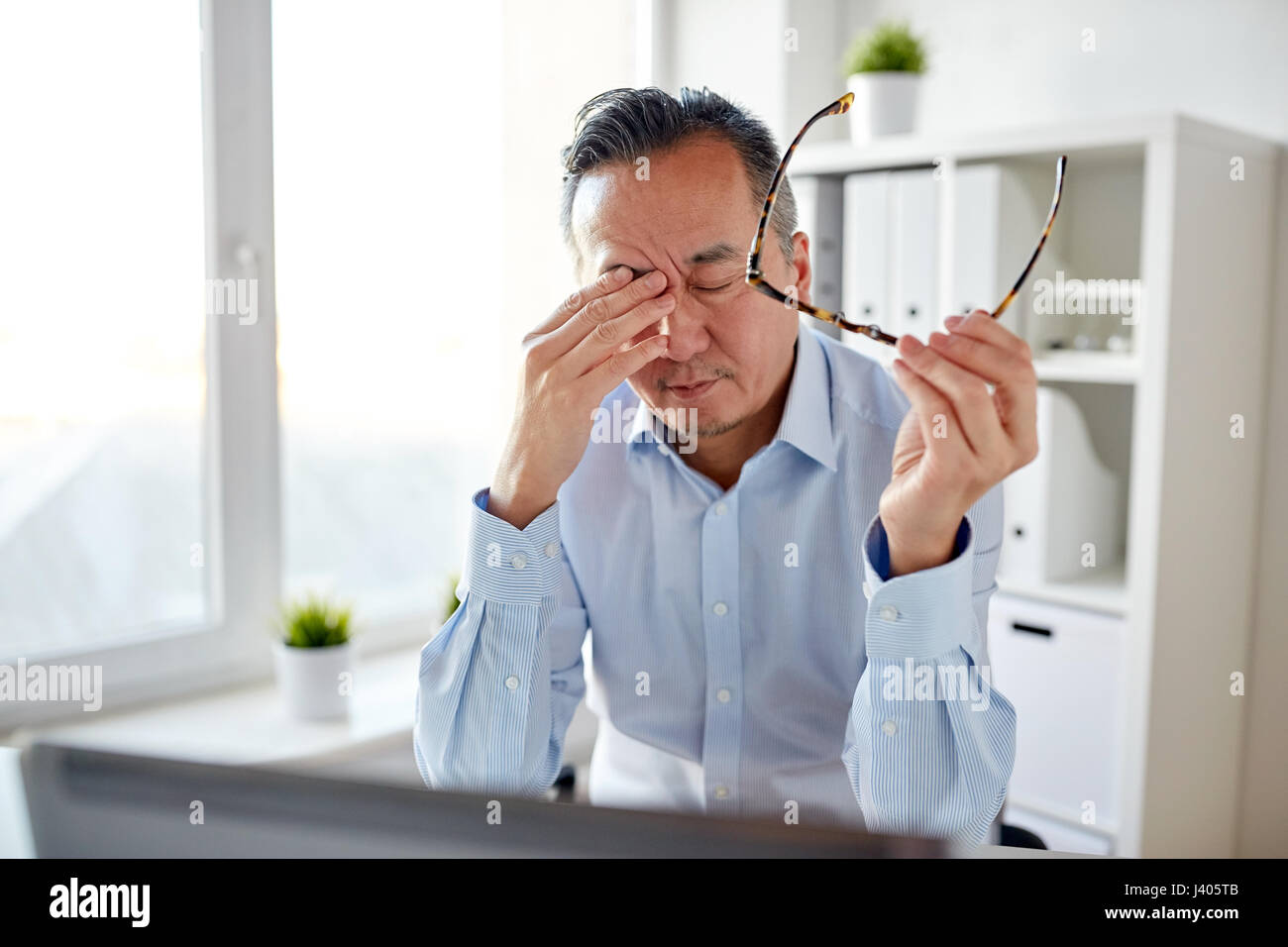 Cansado empresario con gafas al ordenador portátil en la oficina Foto de stock