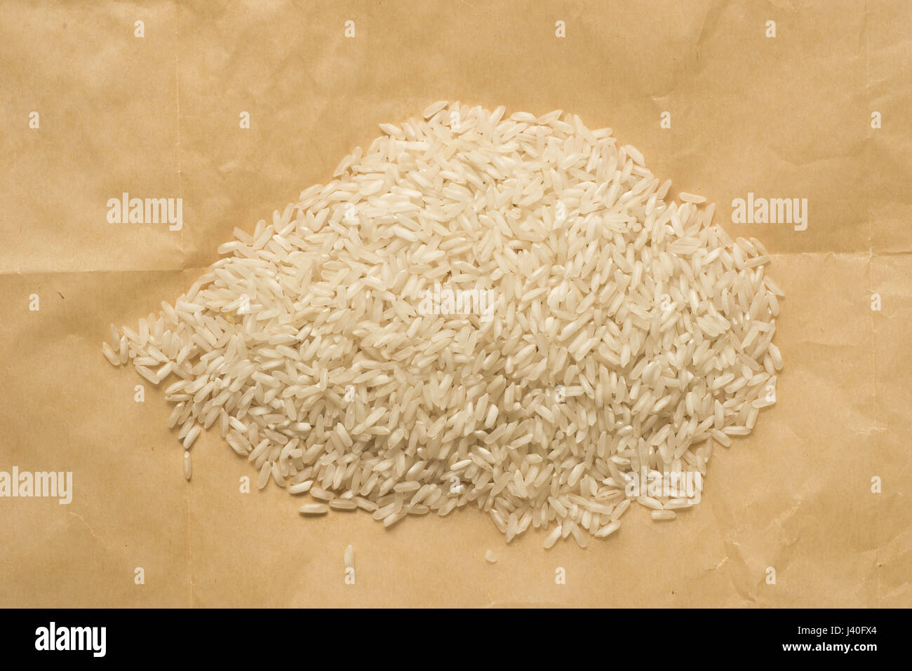 Montón de arroz crudo seco sobre papel marrón Foto de stock