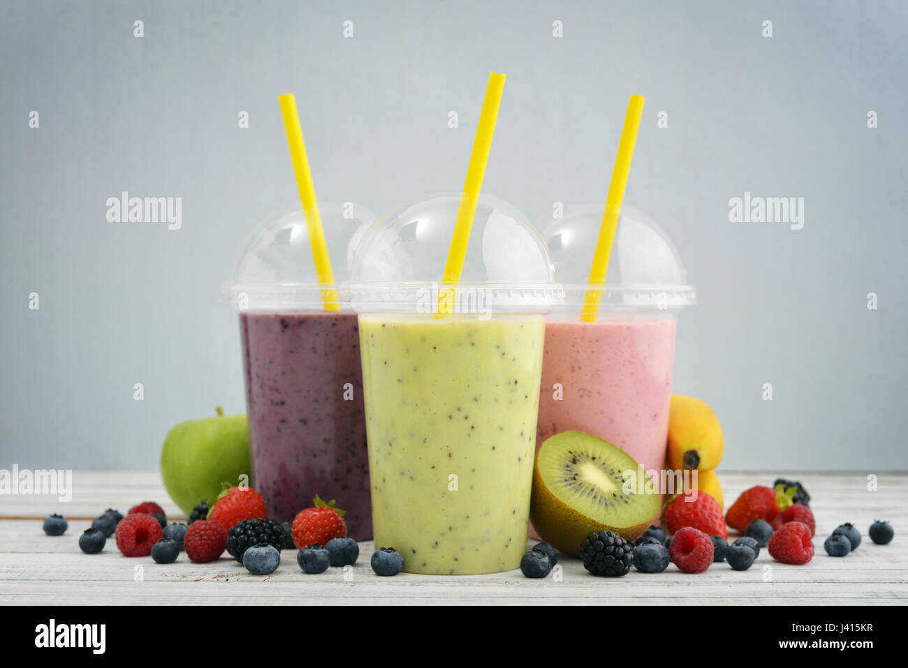 Licuados de frutas en vasos de plástico con arándanos, fresas, frambuesas,  moras, kiwi y plátano sobre fondo azul. Llevar bebidas concepto Fotografía  de stock - Alamy