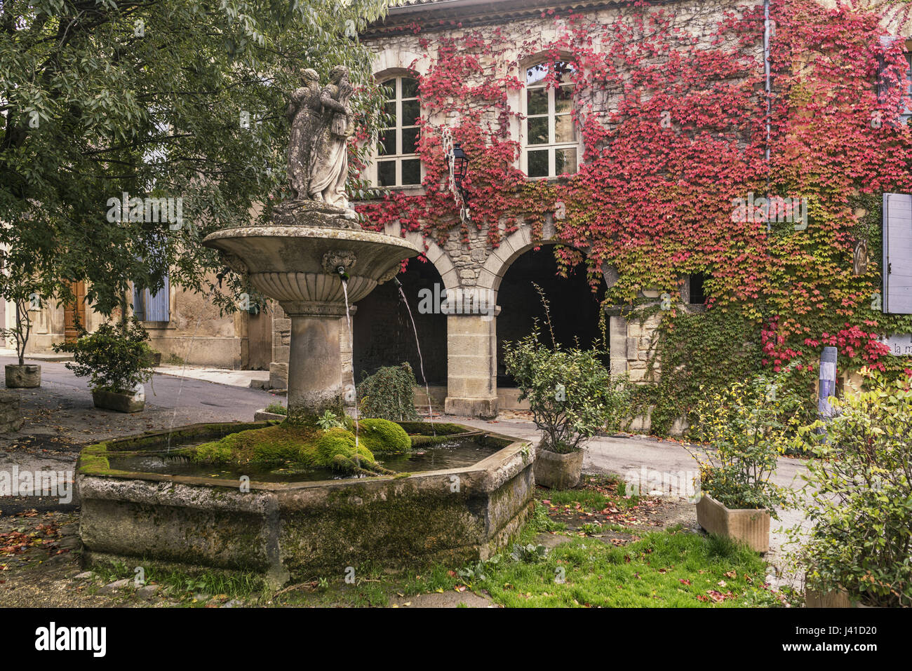 Fuente en Saignon, fachada con wild vino en otoño, Provence-Alpes-Côte d'Azur, Francia Foto de stock