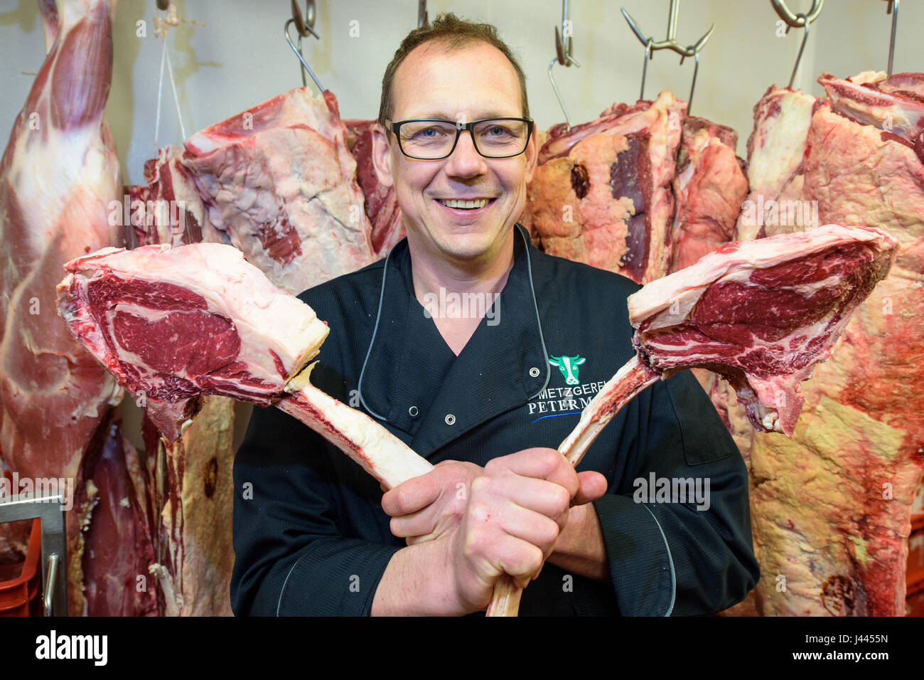 Oberwurzbach, Alemania. 26 abr, 2017. Maestro carnicero Thomas Petermann  tiene en sus manos dos llamados Tomahaw bistecs en el congelador de su  carnicería en Oberwurzbach, Alemania, el 26 de abril de 2017.