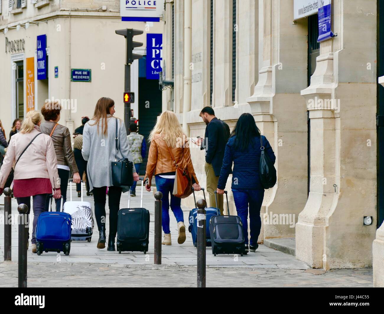 Grupo de mujeres jalando maletas con ruedas en la acera en frente del  ayuntamiento del distrito 6, Rue Bonaparte, París, Francia Fotografía de  stock - Alamy