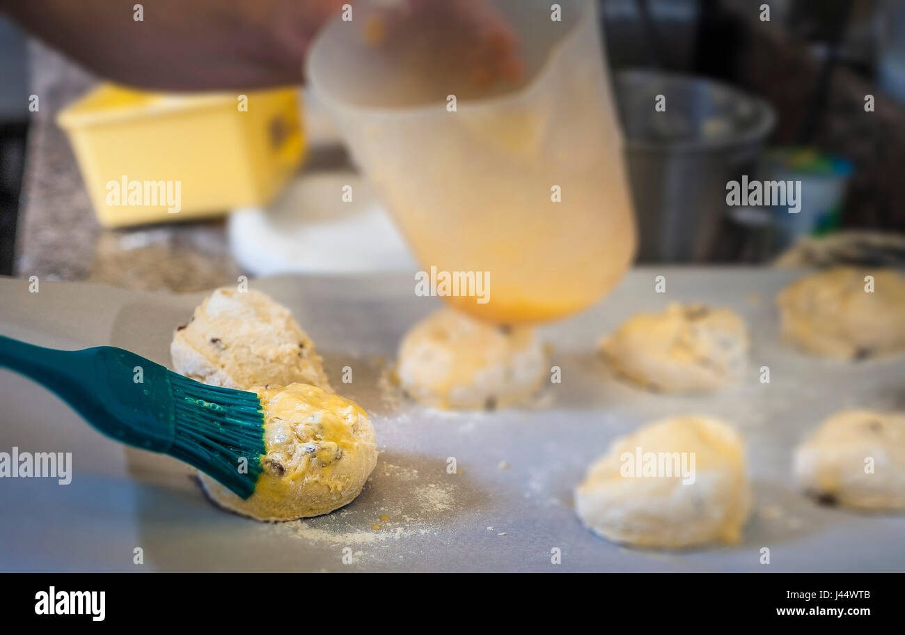 Un chef aplica un huevo lavar a scone masa Cocina Comida Restaurante para hornear preparación Alimenticia Industria Alimentaria Trabajador Foto de stock