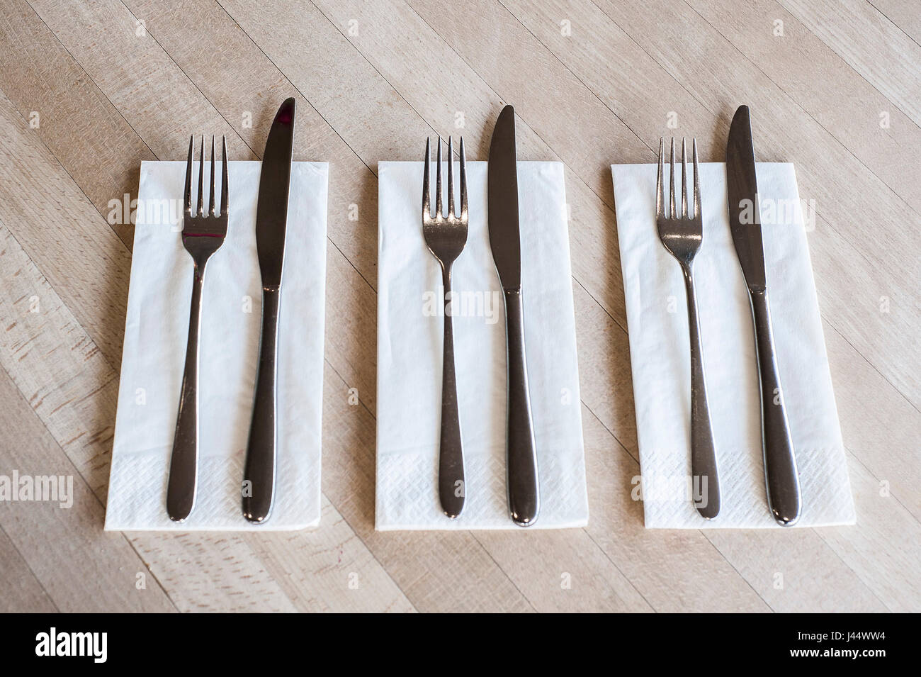 Cubiertos en una mesa en un restaurante de cuchillas horquillas servilletas servilletas limpias sin usar utensilios Foto de stock