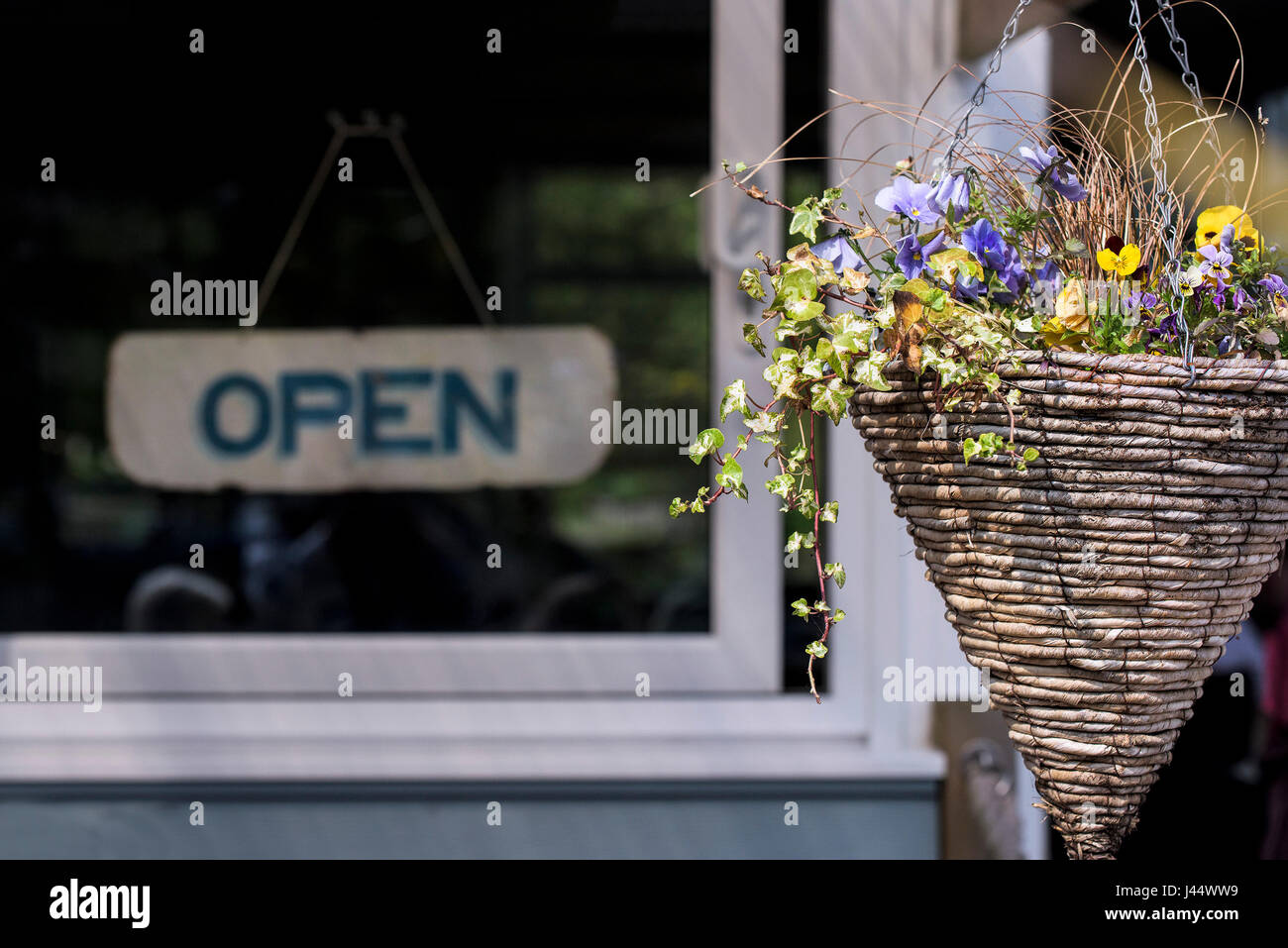 Una cesta colgante con coloridas flores Restaurante Cafetería abierta signo Decoración Foto de stock