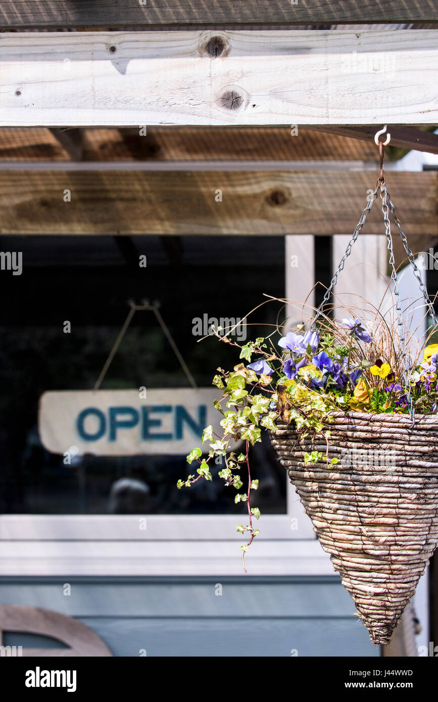 Una cesta colgante con coloridas flores Restaurante Cafetería abierta signo Decoración Foto de stock