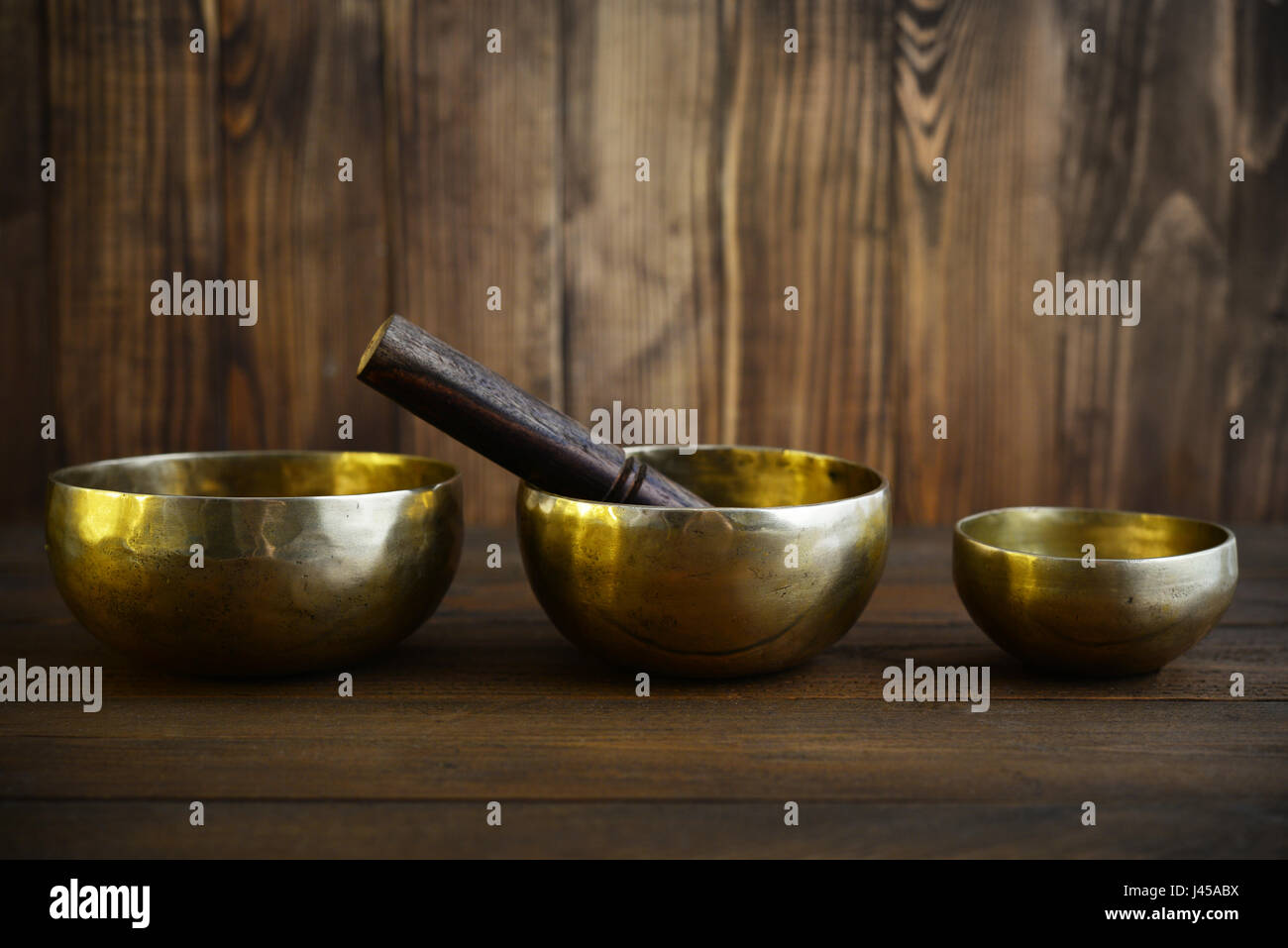 Handcrafted cuencos tibetanos cantando con palos de fondo de madera Foto de stock