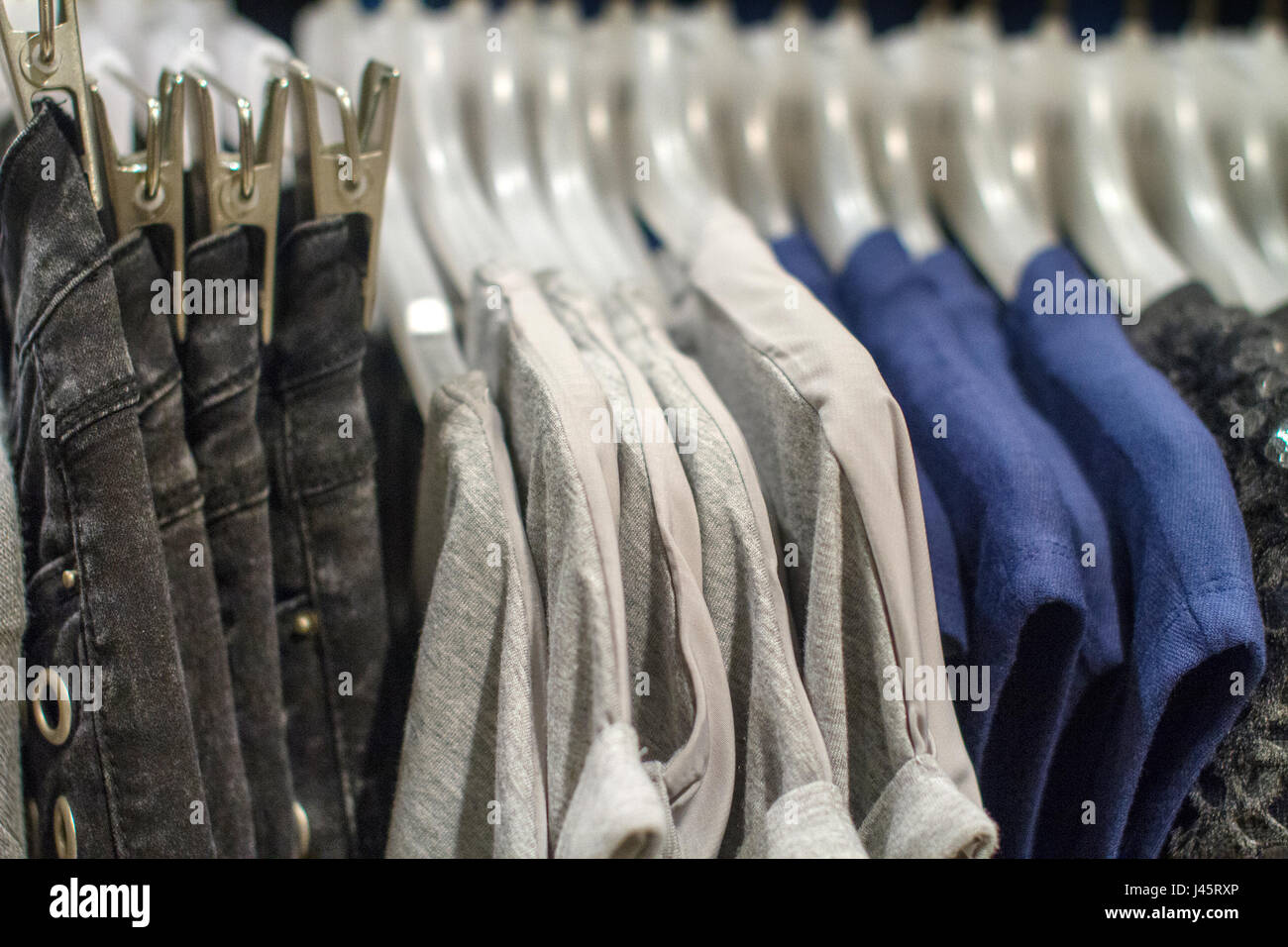 Imagen de vaqueros y camisetas colgando de un gancho en la tienda Foto de stock