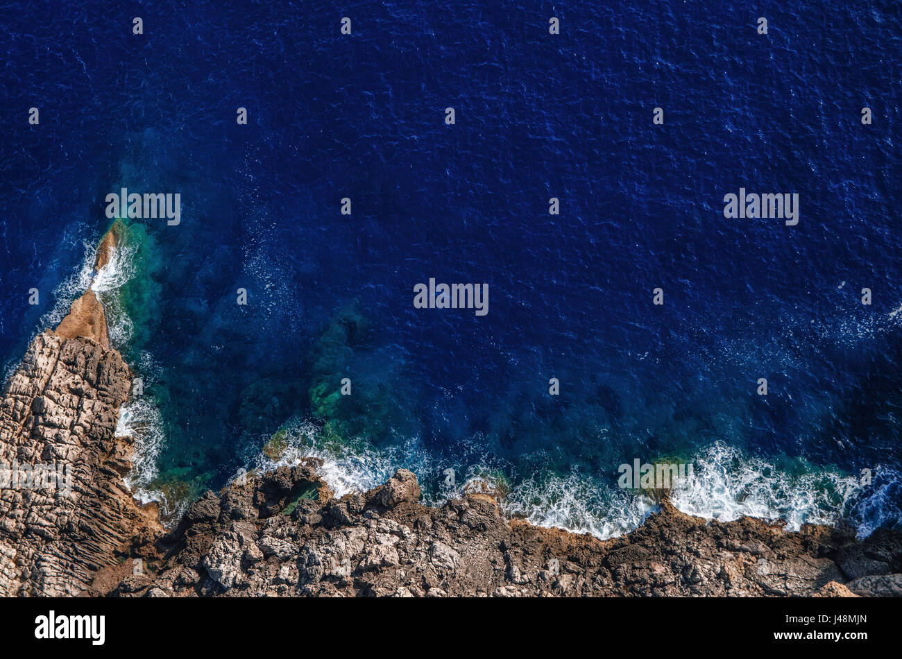 Olas rompiendo sobre las rocas en la orilla con espuma de mar, Mallorca Foto de stock