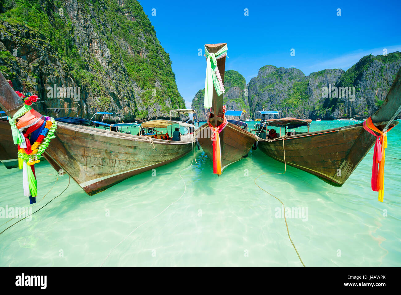 "Longtail" de madera tradicional tailandesa con coloridos barcos fajas en las turquesas aguas de Andaman de Maya Bay, en el sur de Tailandia Foto de stock